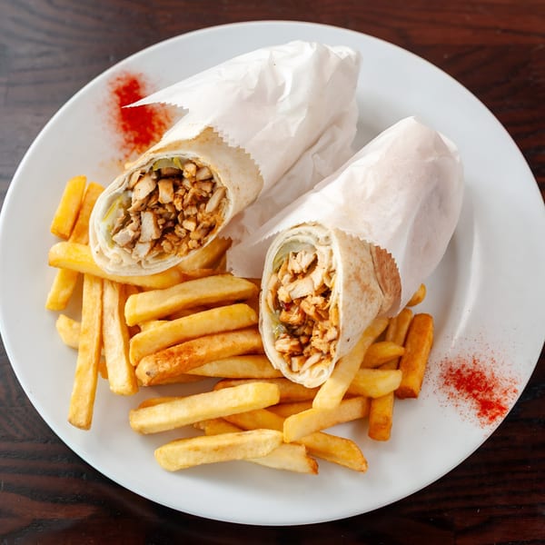 Two Kabobji chicken shawarma wraps with crispy french fries on a white plate.