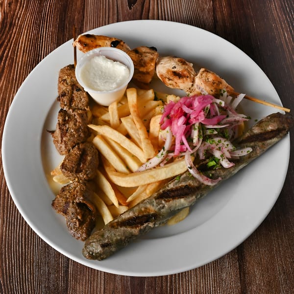Kabobji's mixed grill platter with chicken and beef skewers, kofta, fries, pickled onions, and garlic sauce.